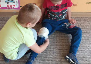 chłopiec zawija kolano bandażem
